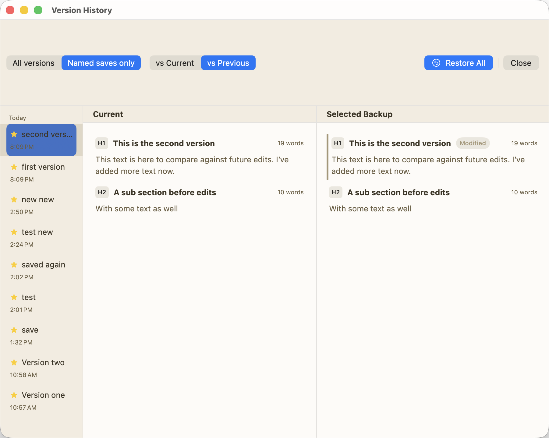 Version History panel showing a list of named saves on the left (second version, first version, new new, test new, etc.) with timestamps. The main area compares the current document against a selected backup side by side. The current version shows: heading 'This is the second version' with body text 'This text is here to compare against future edits. I've added more text now.' and a sub section 'A sub section before edits' with 'With some text as well.' The selected backup shows the same structure with a 'Modified' badge on the heading, indicating changes between versions. Filter buttons at top allow viewing all versions or named saves only, and comparing against current or previous versions, with a Restore All option.